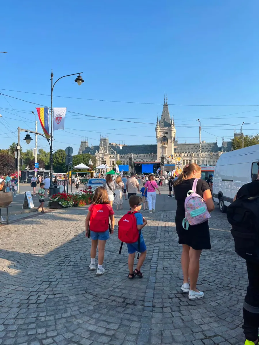 Pietonalul Ștefan cel Mare din Iași în timpul festivalului, cu Palatul Culturii în fundal și copii cu rucsacuri Amma roșii
