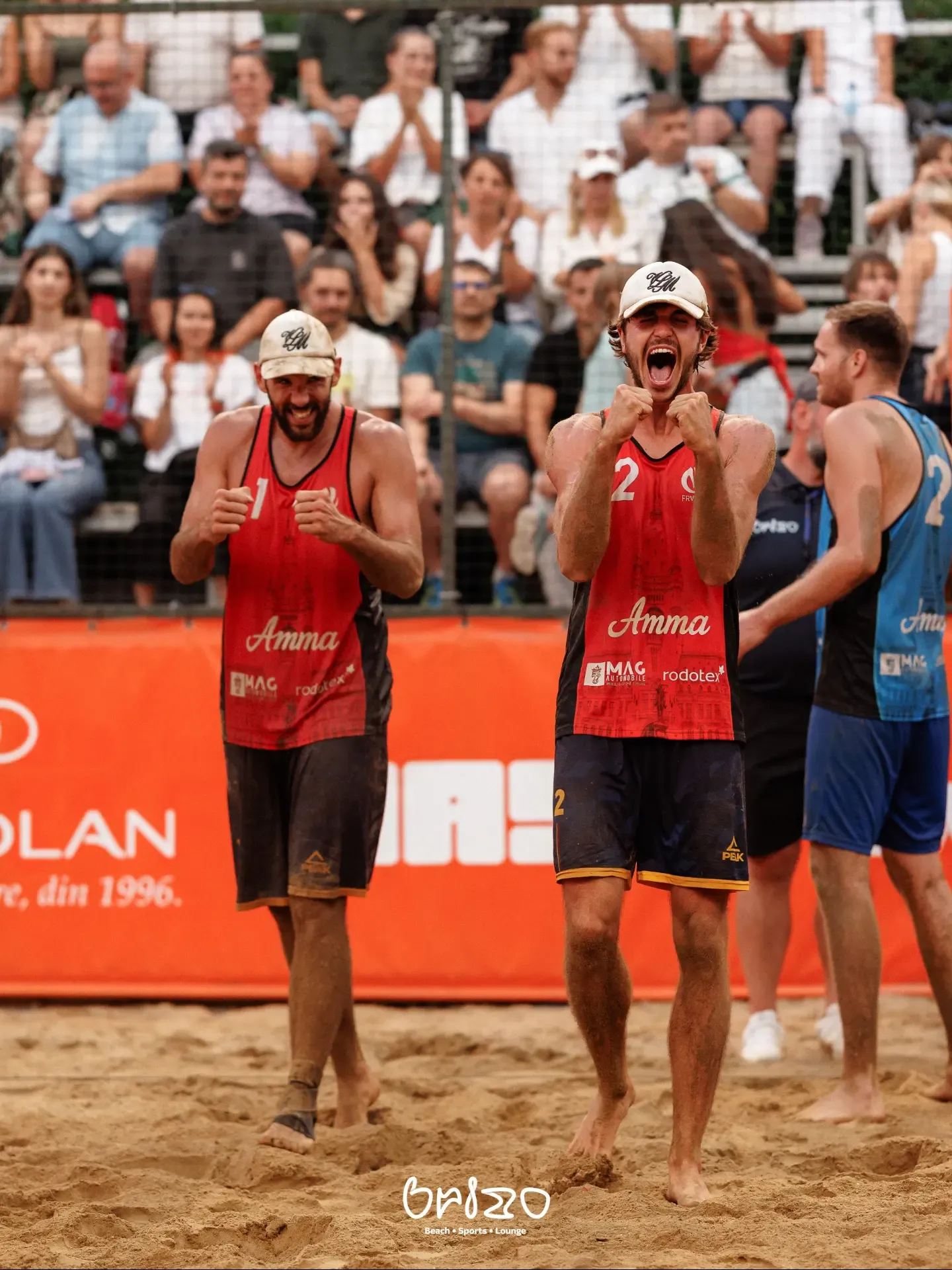 Jucători de volei pe plajă bucurându-se de un punct, în fața tribunelor pline