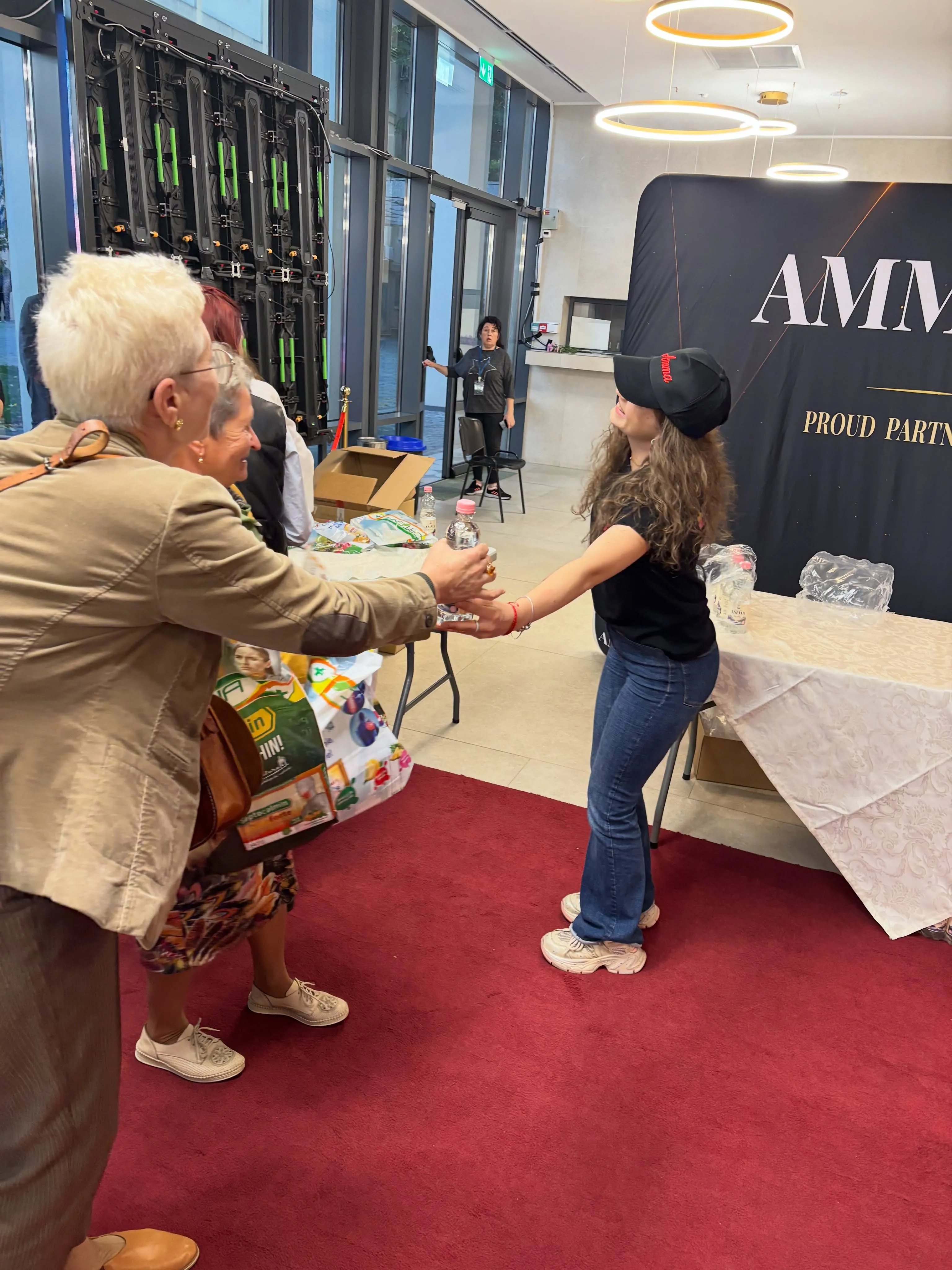 O doamnă salutând echipa de la standul Amma