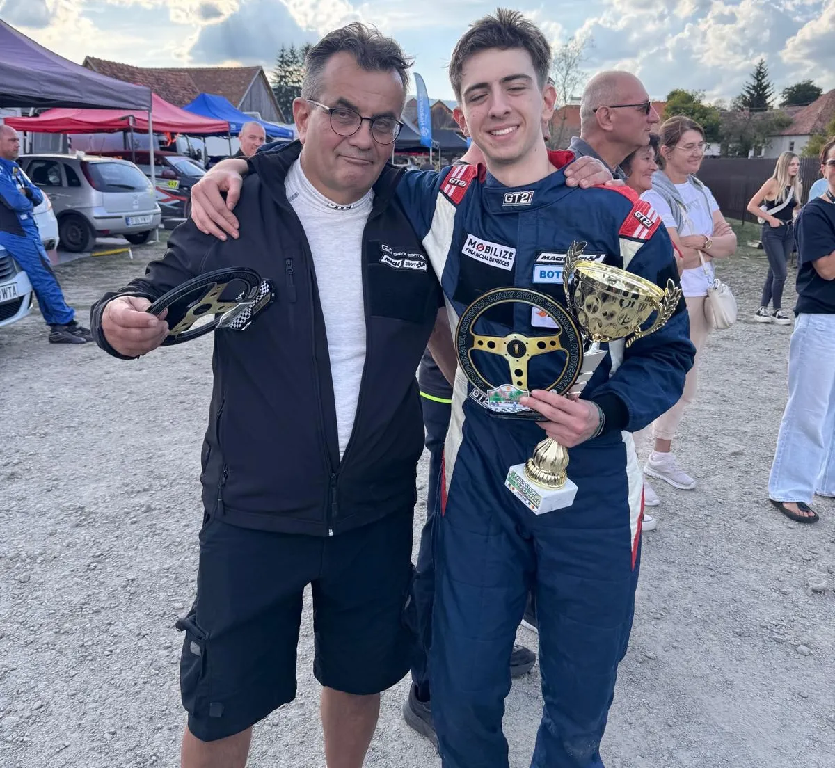 Matei Botea cu trofeul și volanul de câștigător, alături de un coechipier